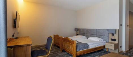 Ein Hotelzimmer mit einem hölzernen Bett, einem Schreibtisch, einem Stuhl und einem kleinen Tisch.