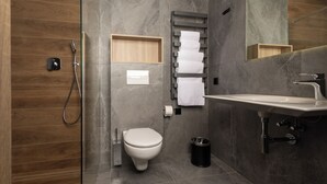 Une salle de bain moderne équipée d’une douche, de toilettes, d’un lavabo et d’un porte-serviettes.