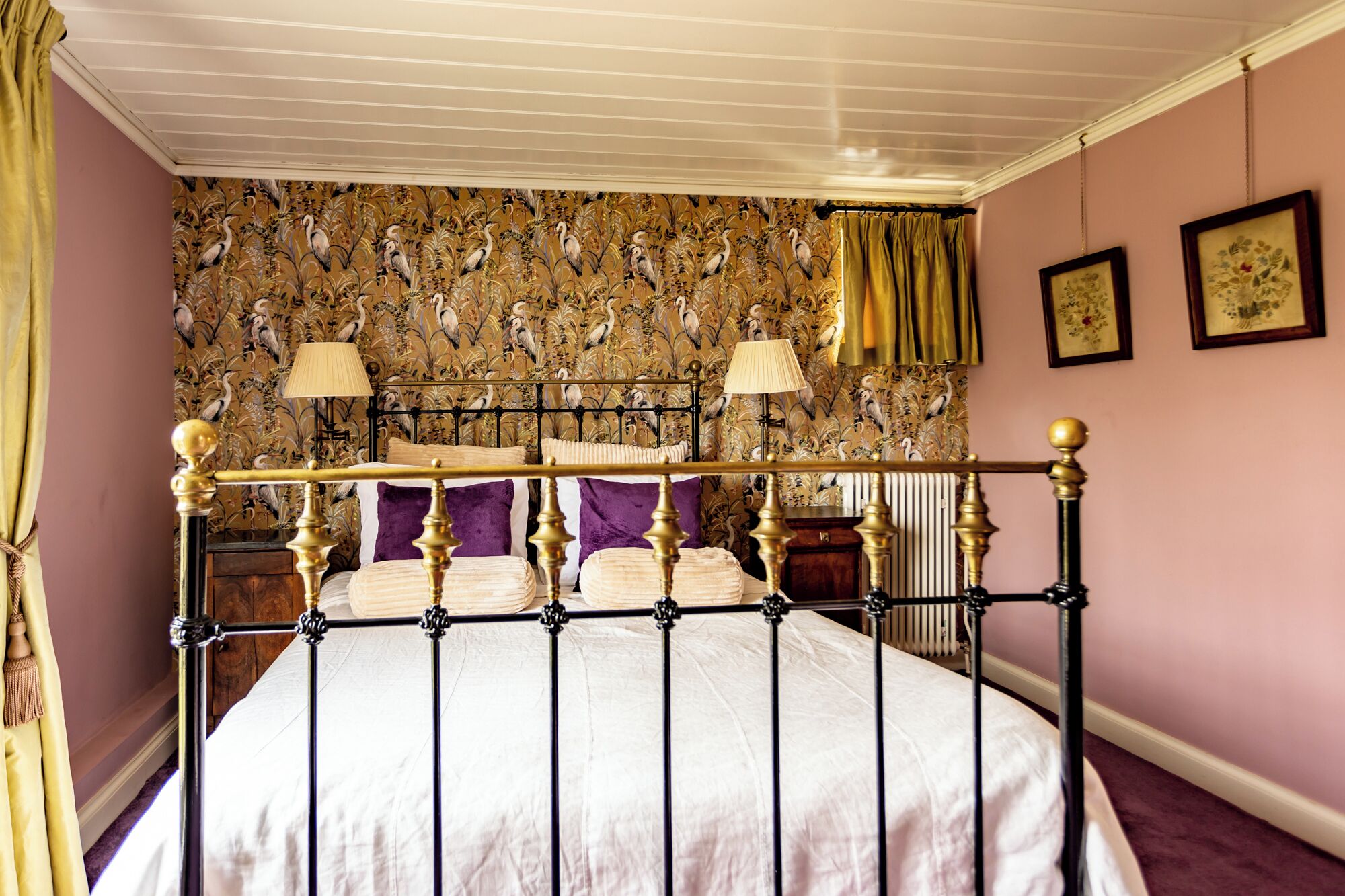 Une chambre à coucher avec un lit à baldaquin, un papier peint à motifs floraux et deux lampes de chevet.