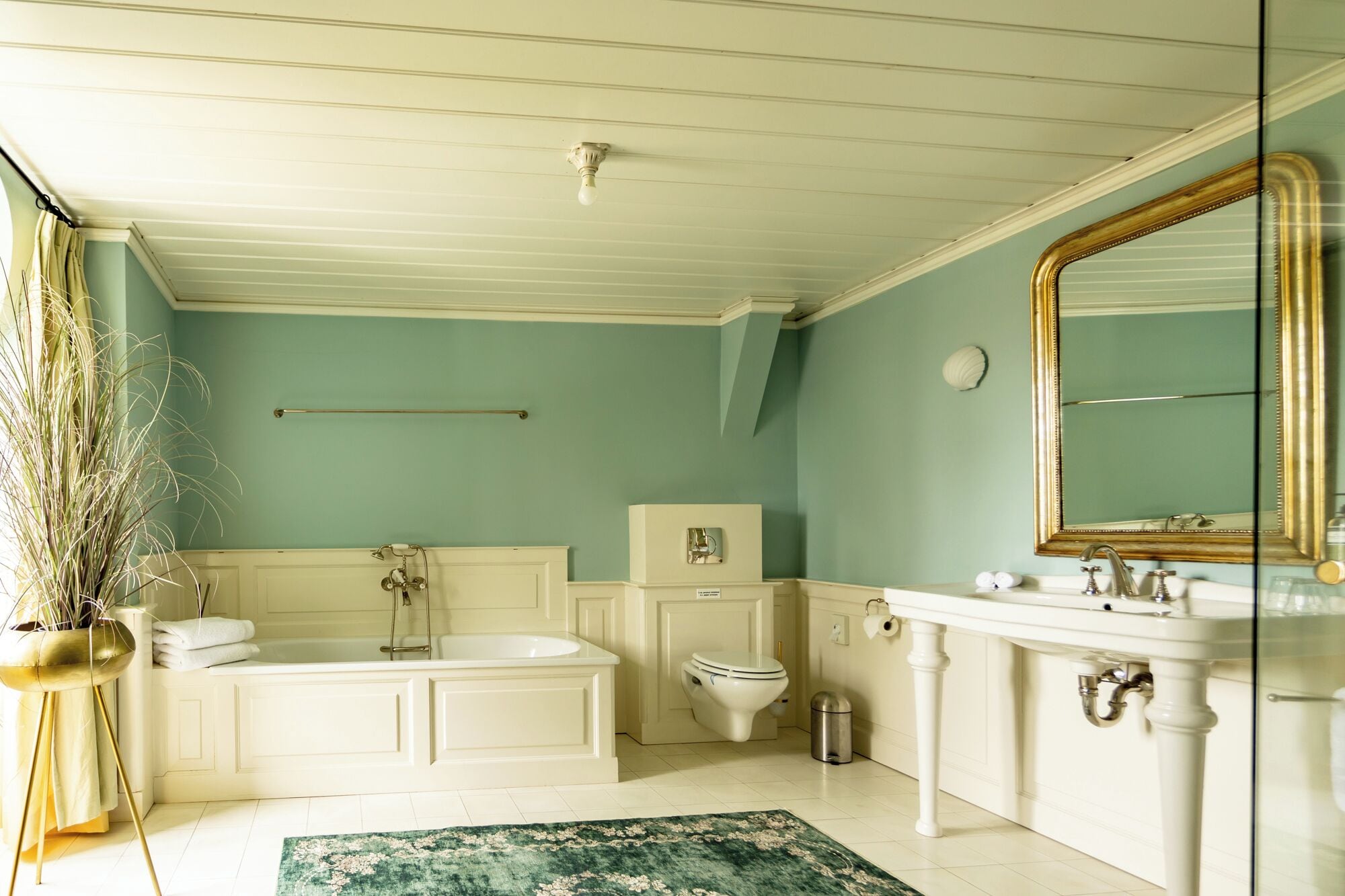 A bathroom with a bathtub, toilet, sink, and a large mirror.