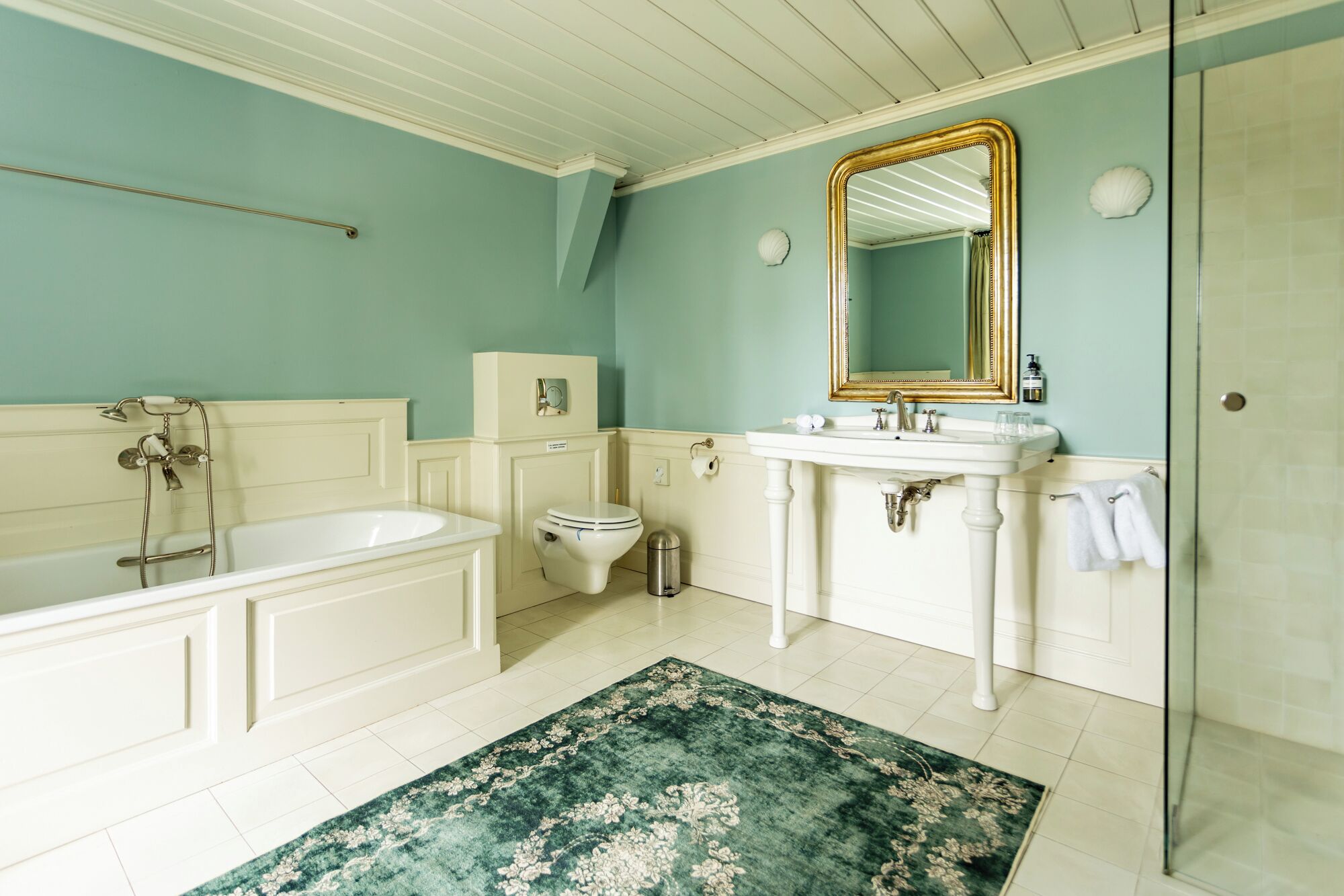 Un baño con bañera, inodoro, lavabo y un espejo grande.