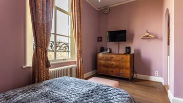 A bedroom with a bed, a dresser, a television, and a radiator.