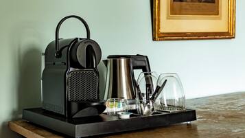 A coffee machine, a kettle, and a tray with glasses and utensils on a table.