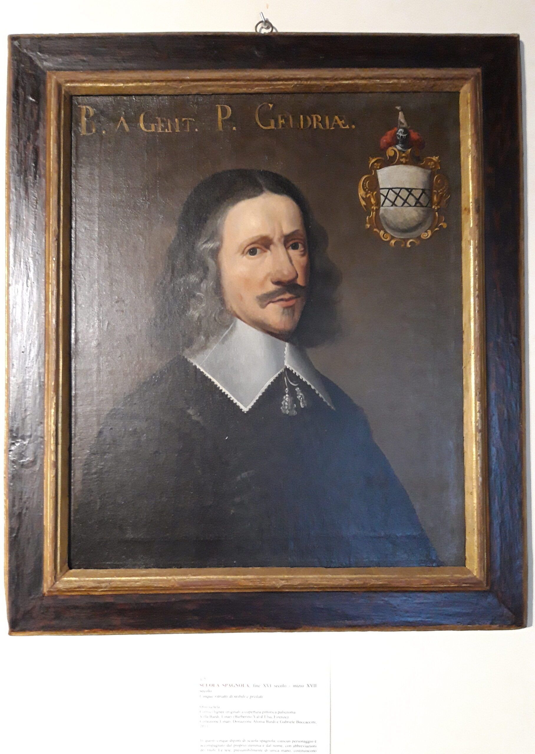 Retrato enmarco de un hombre con bigote, usando un abrigo azul oscuro con cuello blanco.