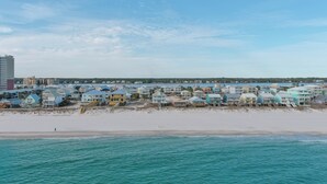 A coastal area with beachfront properties, a sandy beach, and a clear blue sky.