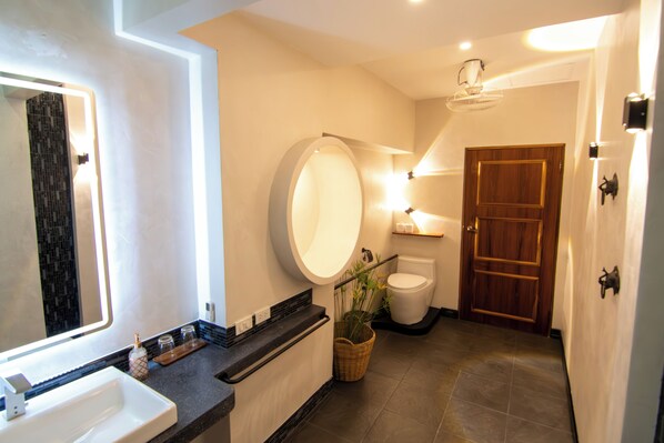A modern bathroom with a large mirror, a round vanity, a toilet, and a wooden door. - La Belle Vie - Boutique Hotel (Ko Pha-ngan)