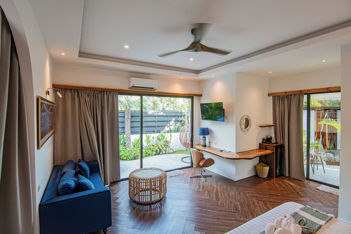 A modern room with a sofa, a round table, a desk, and a ceiling fan.