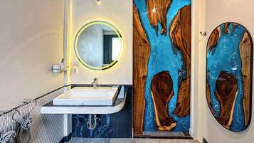 A bathroom with a white sink, a round mirror, and a unique wooden door with a blue inlay.