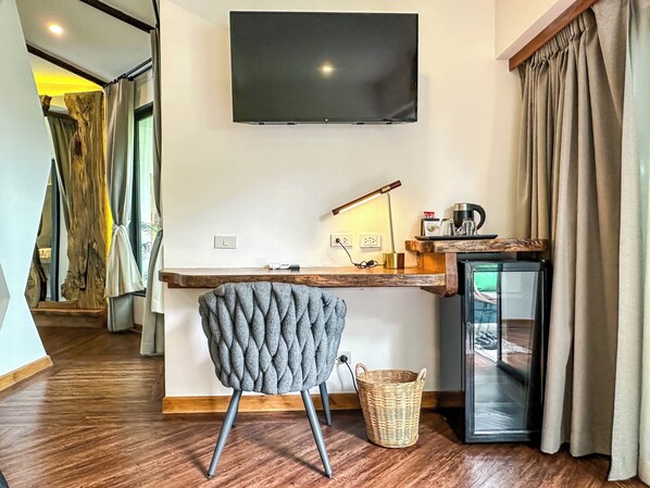 A modern room with a flat-screen TV mounted on the wall, a wooden desk with a lamp, a chair, and a small refrigerator. - La Belle Vie - Boutique Hotel (Ko Pha-ngan)