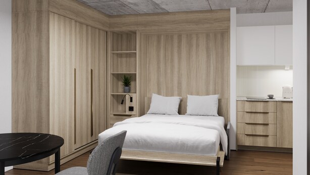 Ein modernes Schlafzimmer mit Bett, Nachttischen, einem kleinen Schreibtisch und einer Küchenzeile.