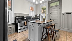 Una cucina con isola centrale, elettrodomestici in acciaio inossidabile e un lampadario a sospensione.