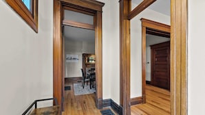 Un corridoio con pavimento in legno e porte che conducono a una sala da pranzo.