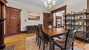 Una sala da pranzo con un tavolo in legno, sedie, un lampadario e una libreria.