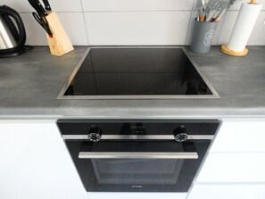 Eine Küche mit eingebautem Kochfeld und Backofen, einem Messerblock und einem Besteckhalter.