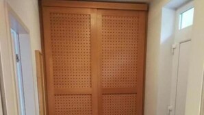 Ein Flur mit einem Holzschrank, einer schwarzen Matte auf dem Boden und einem Metallregal.
