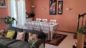 Un salon comprenant un canapé, une table à manger avec des chaises, un escalier et un mur orné de deux tableaux encadrés.
