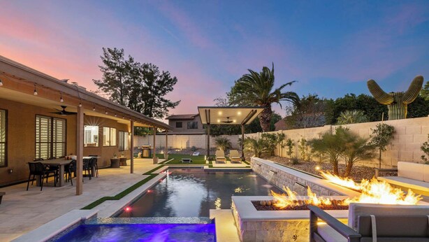 A pool with a waterfall feature, a fire pit, outdoor seating, and a covered patio area. - Backyard Bliss: Firepit, Putt, Play, Pool & Spa! (Scottsdale)