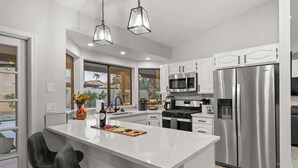 A modern kitchen with a central island, stainless steel appliances, and a view to the outside. - Backyard Bliss: Firepit, Putt, Play, Pool & Spa! (Scottsdale)
