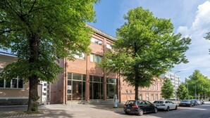 A building with large windows, a brick facade, and a parking lot with cars.