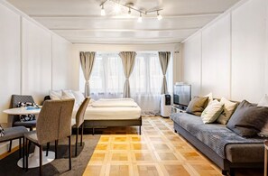 Una habitación de hotel moderna con una cama, un sofá, una mesa de comedor con sillas y un televisor.