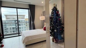 Ein modernes Hotelzimmer mit einem großen Bett, einem Weihnachtsbaum und Blick auf die Stadt durch das Fenster.