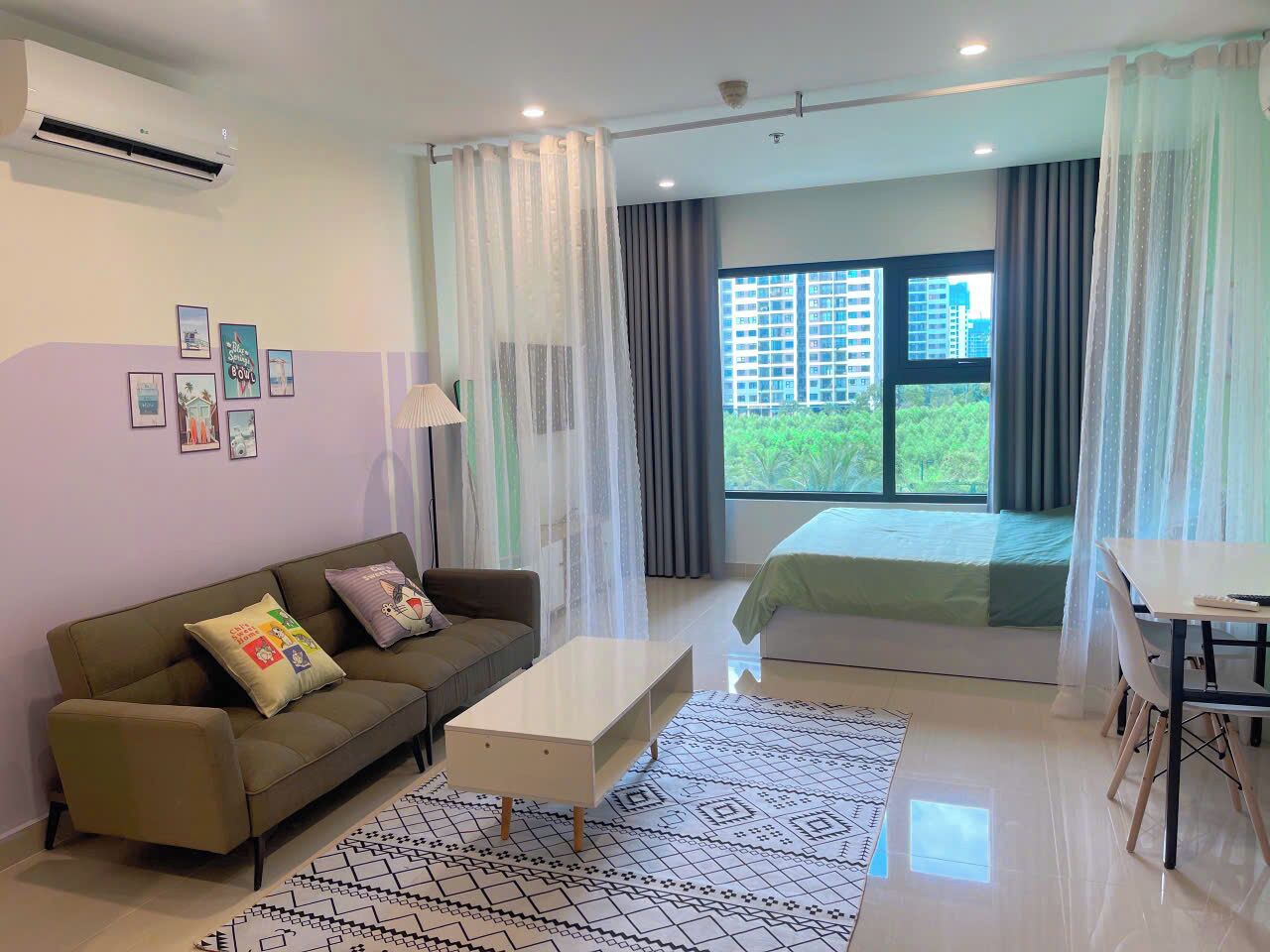A modern hotel room with a sofa, a small table, a bed, and a window with curtains.