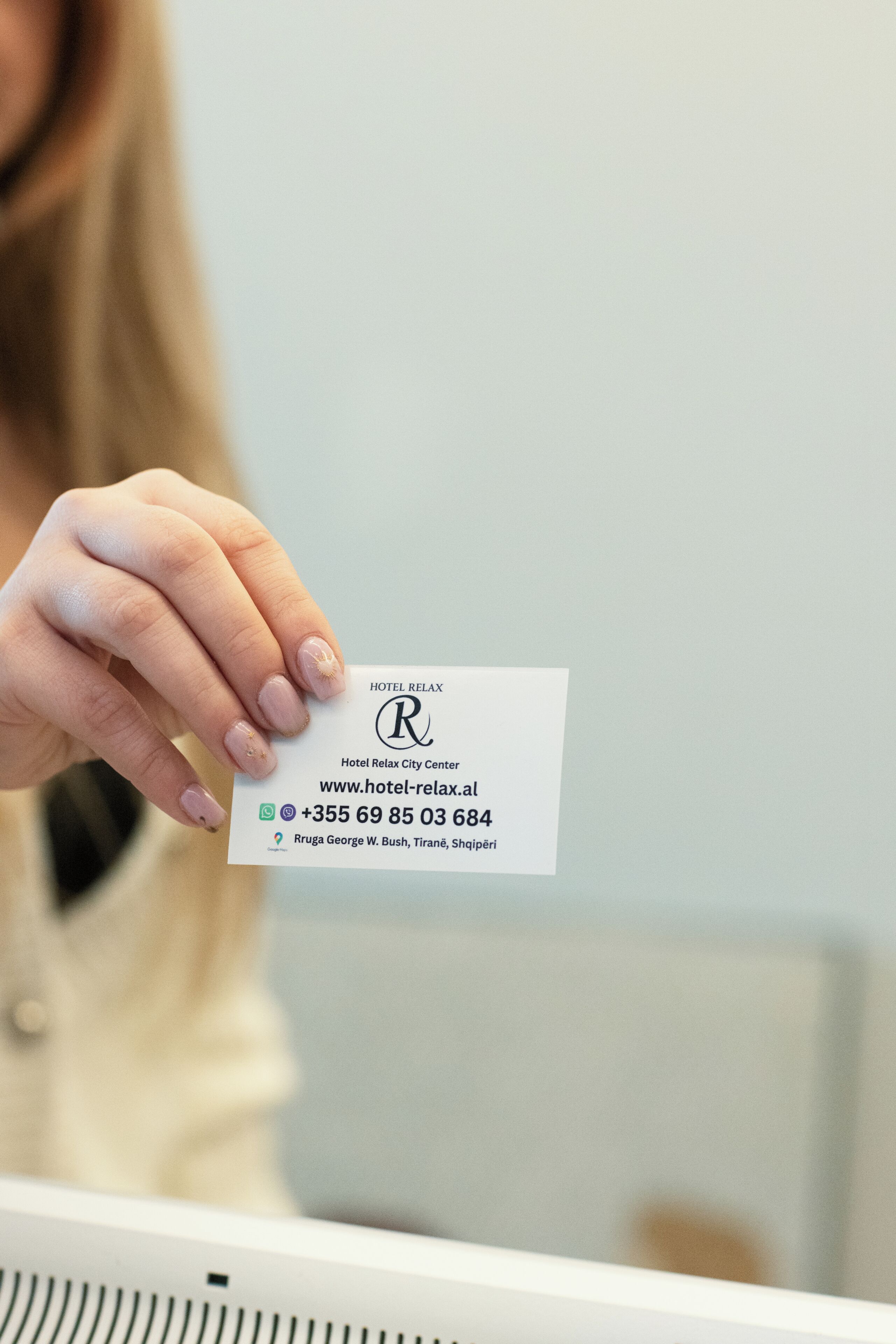 A hand holding a business card for Hotel Relax City Center.
