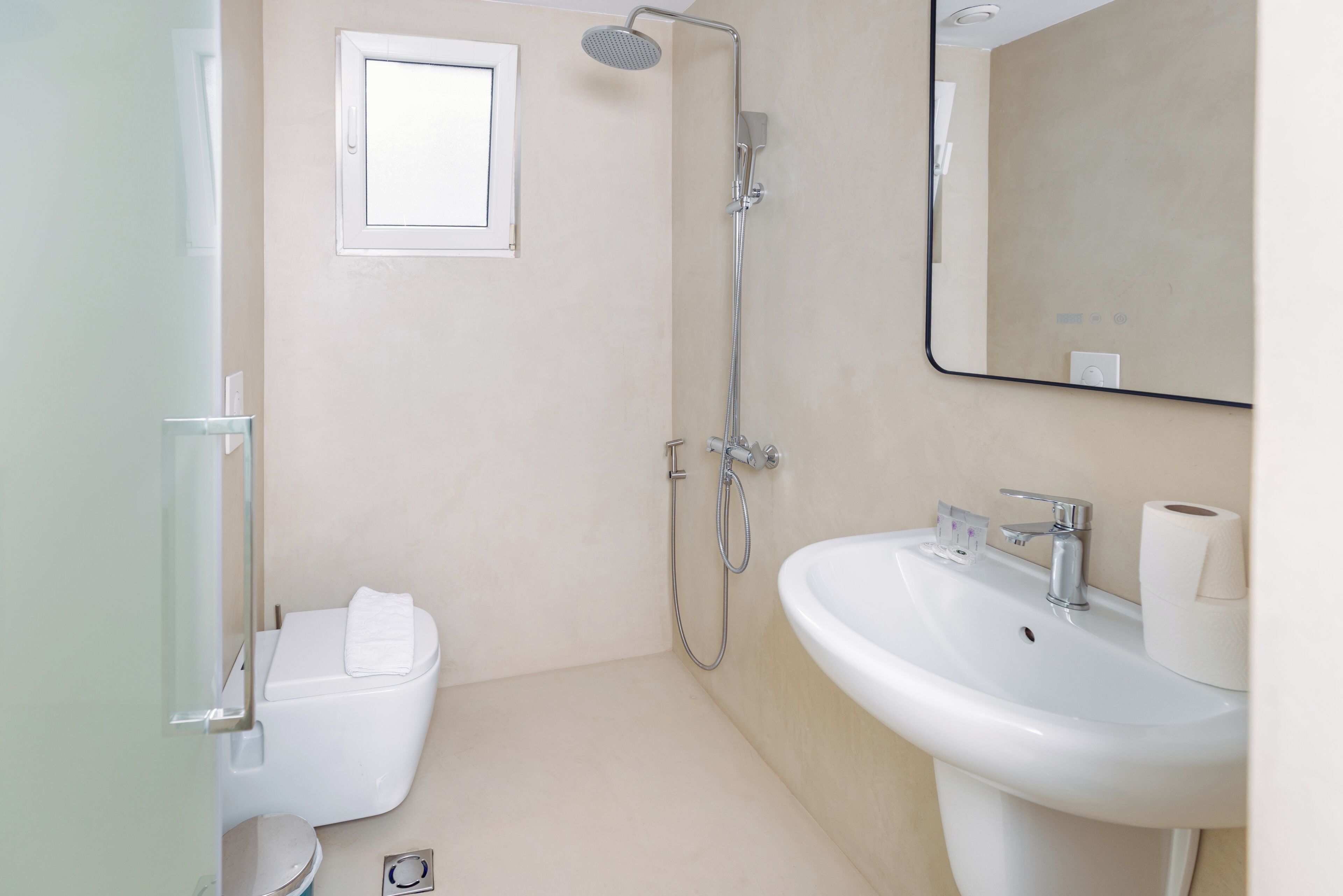 A bathroom with a shower, toilet, sink, and a mirror.