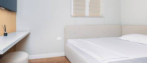 Un dormitorio con cama, escritorio, silla y ventana con persianas.