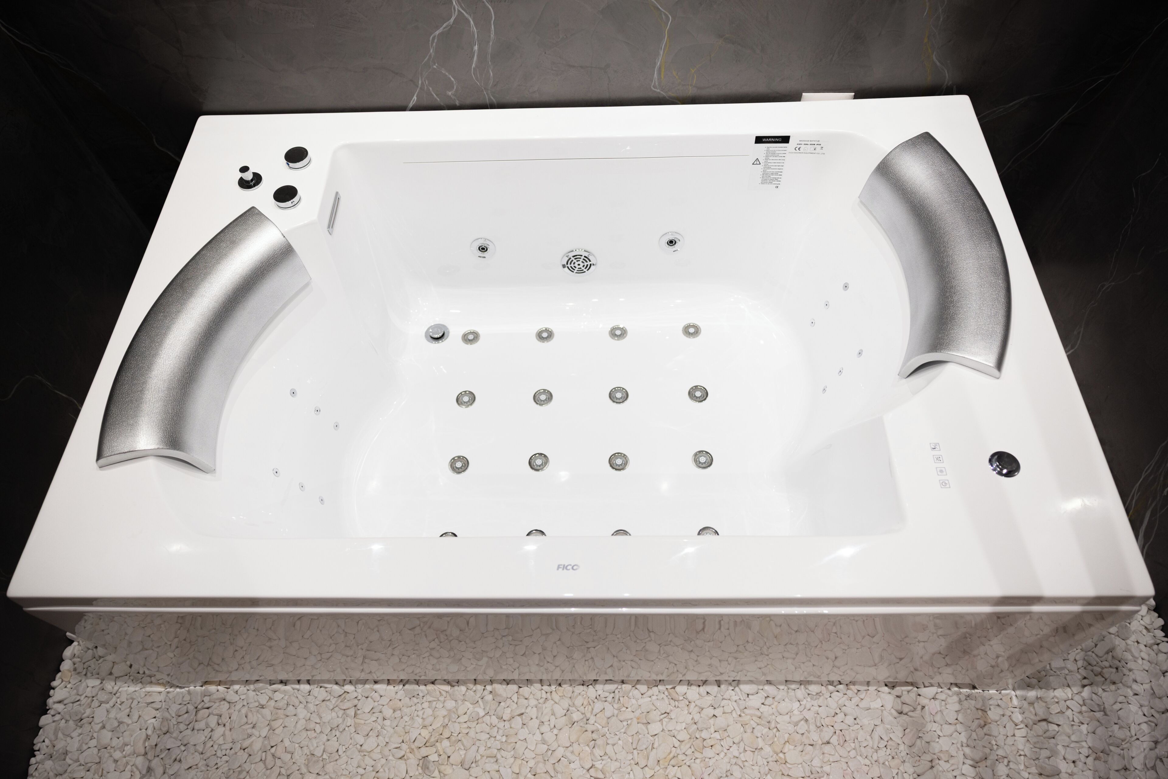 Una bañera blanca con múltiples jets, un panel de control y un piso texturizado.