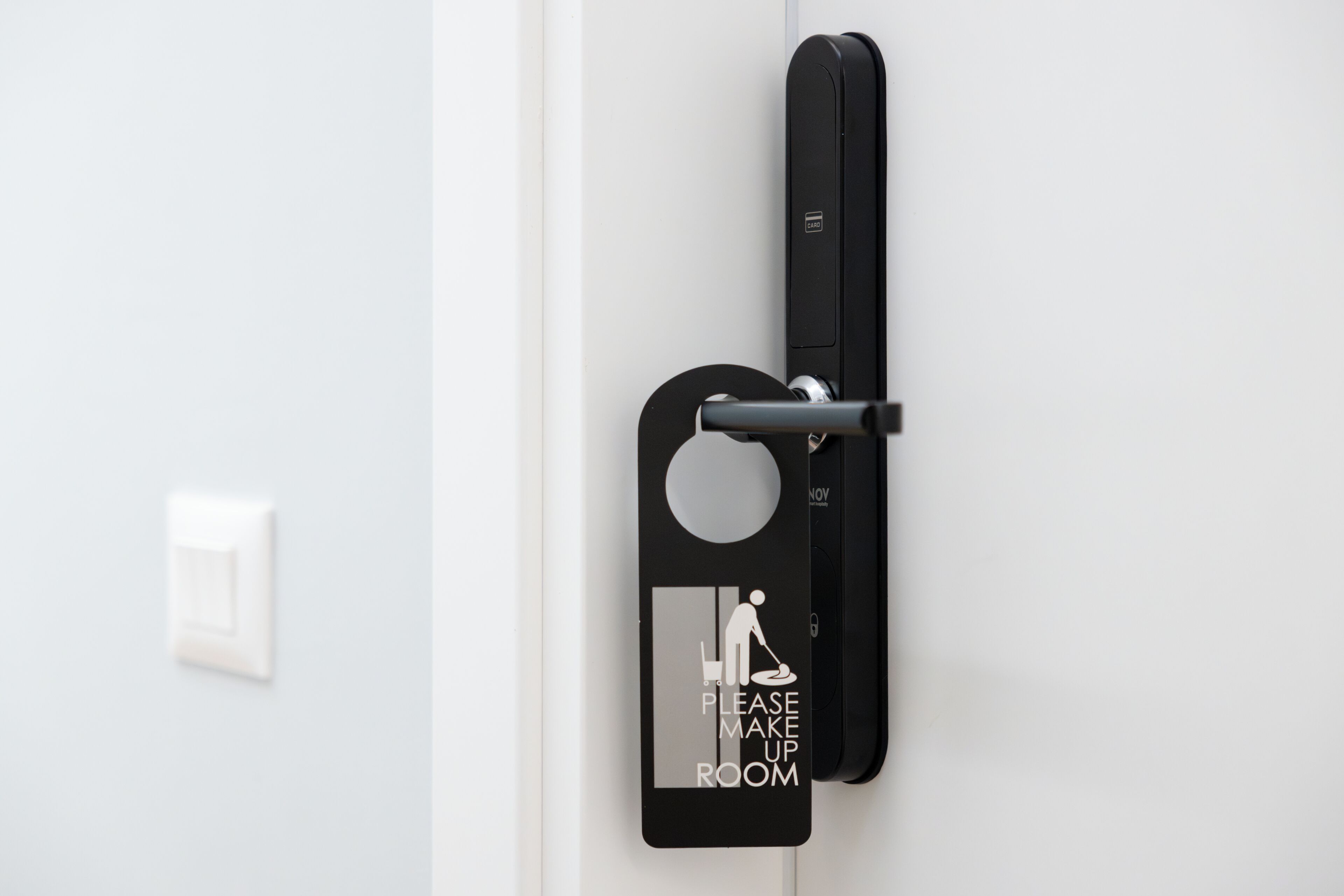 A door with a 'Please Make Up Room' sign and a black intercom system.