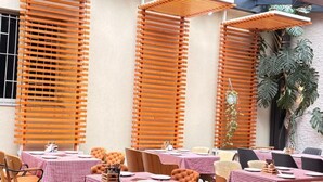 Un comedor interior con manteles a cuadros, sillas de madera y un techo con vigas y luminarias a la vista.
