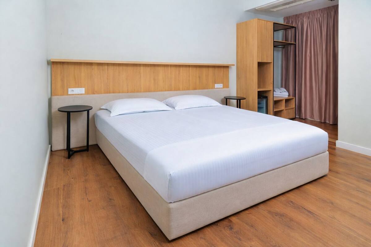 A single bed with a wooden headboard, two bedside tables, and a wardrobe with a mirror.