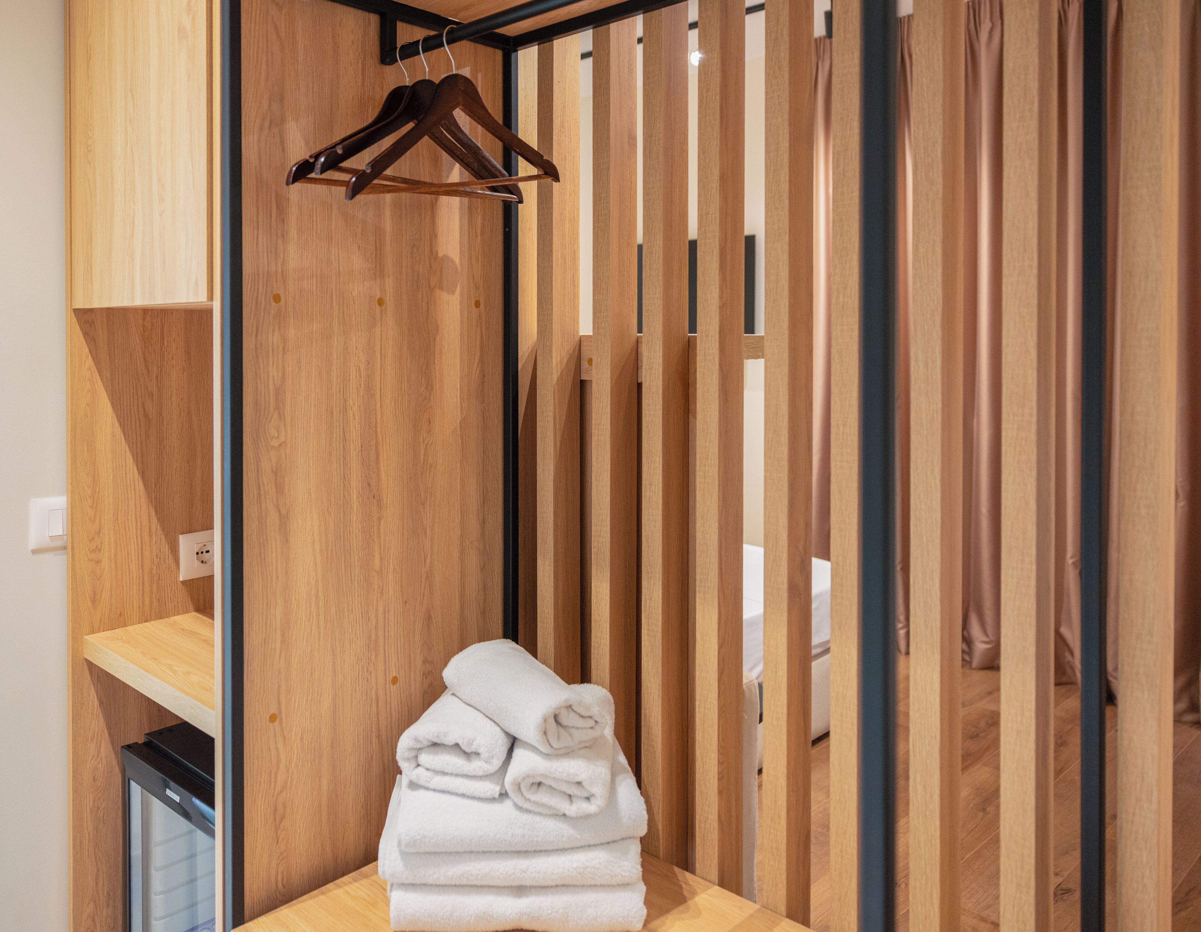 Una habitación de madera con una pila de toallas y un perchero de madera.