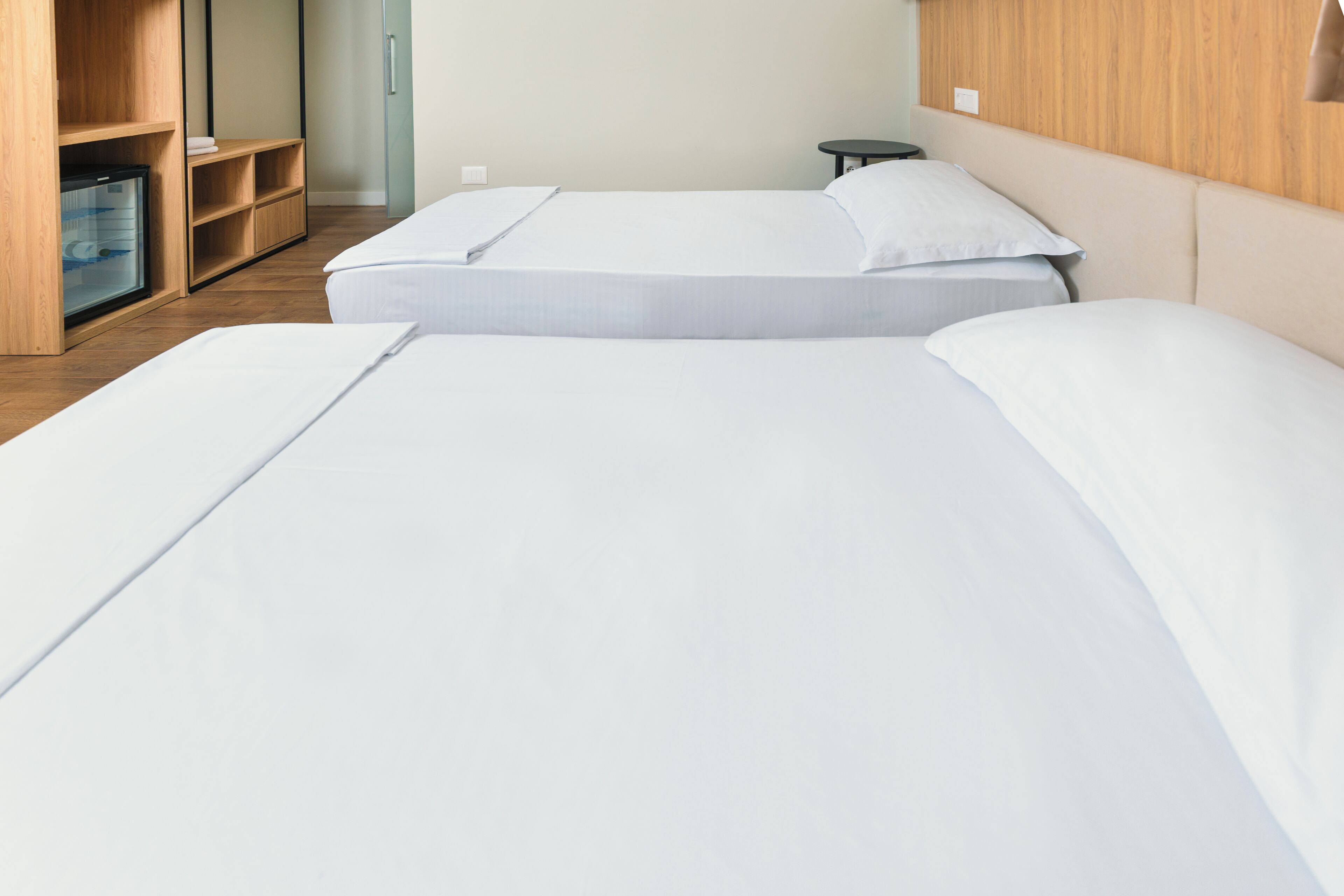 Ein Hotelzimmer mit zwei Betten, einem Holzschrank, einem kleinen Tisch und einer Minibar.