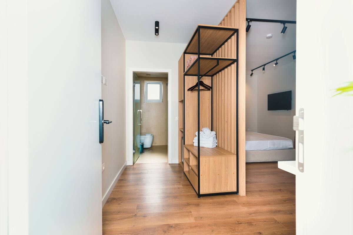 A modern bedroom with a wooden wardrobe, a bed, and a TV mounted on the wall.