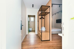 A modern bedroom with a wooden wardrobe, a bed, and a TV mounted on the wall. - Hotel Relax City Center (Tirana)