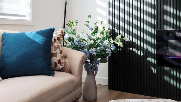 Ein modernes Wohnzimmer mit einer Couch, einem Couchtisch, einer Stehlampe und einer Vase mit Blumen.