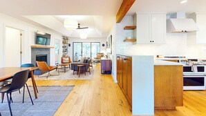 Una cocina moderna con armarios de madera, horno empotrado y comedor con mesa y sillas de madera.