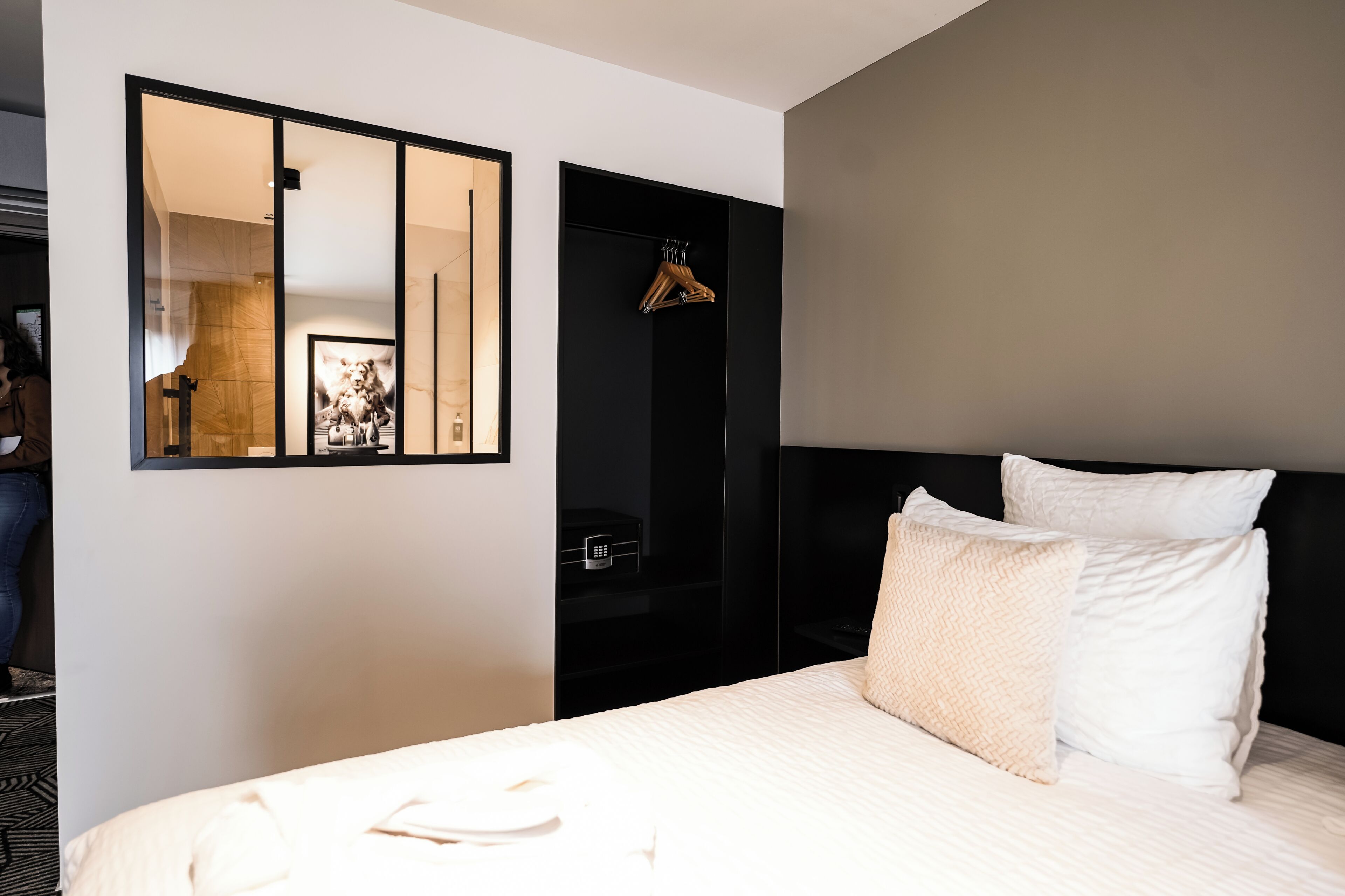 Ein Hotelzimmer mit Bett, Schrank, Spiegel und Kleiderständer.