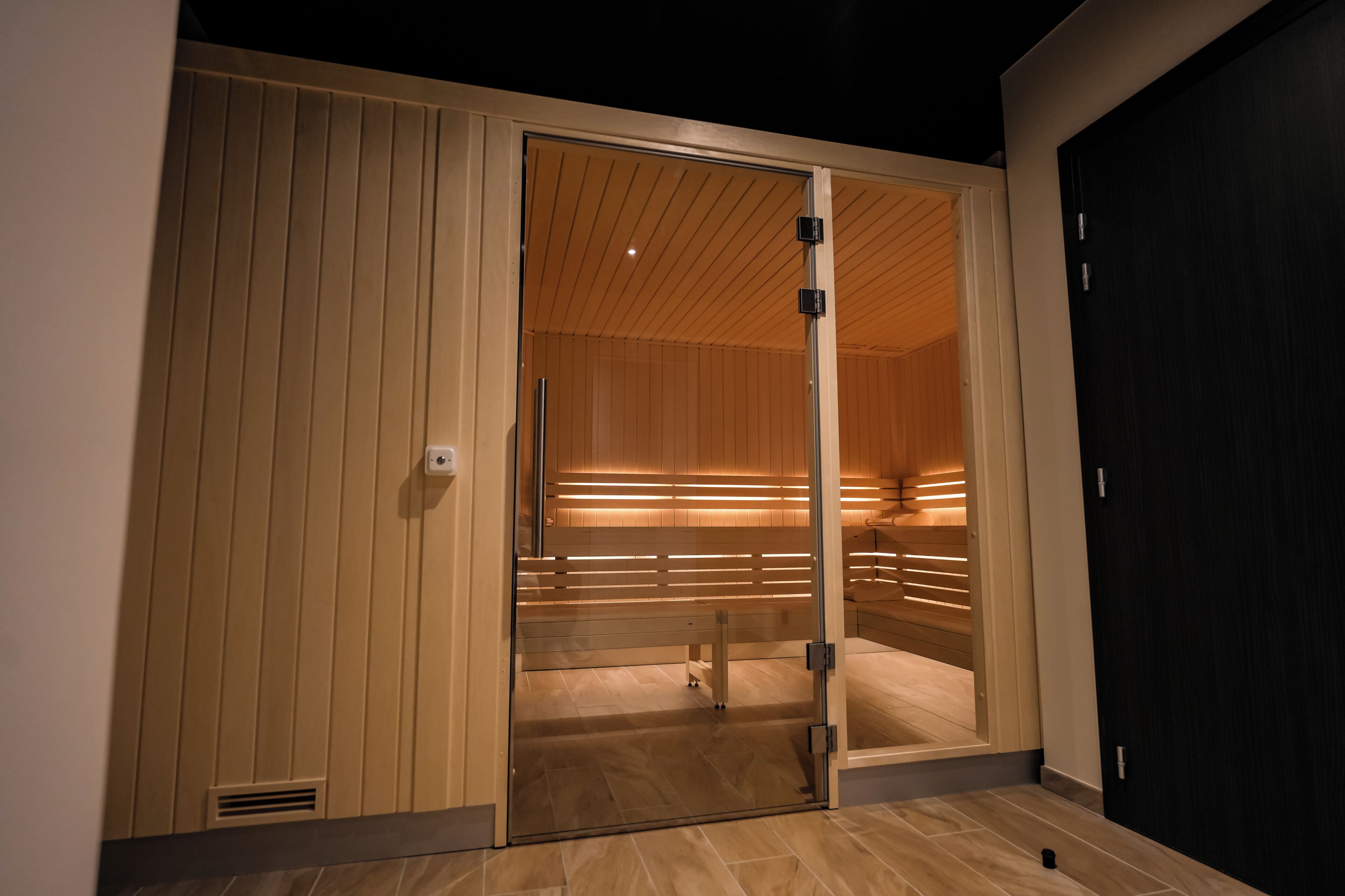 Une chambre moderne dotée d’une porte-fenêtre coulissante donnant accès à un espace sauna en bois.
