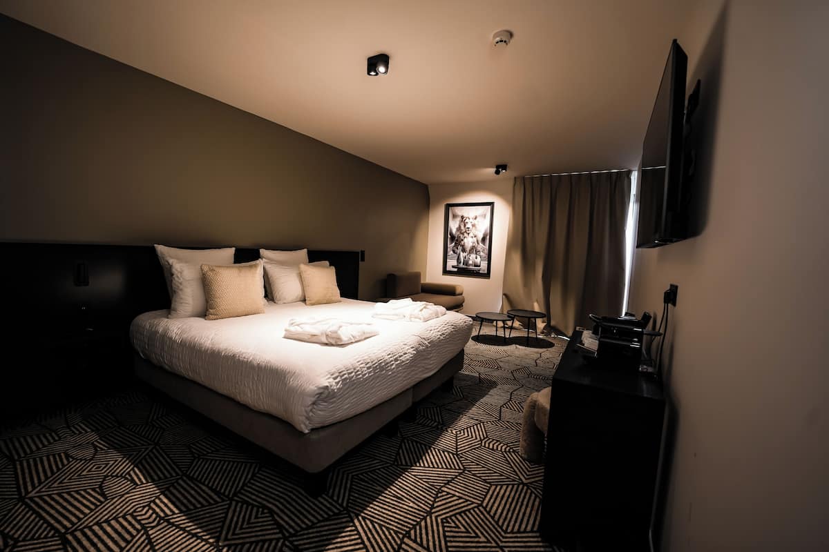 Ein Hotelzimmer mit einem großen Bett, einem Schreibtisch, einem Stuhl und einem Fernseher.