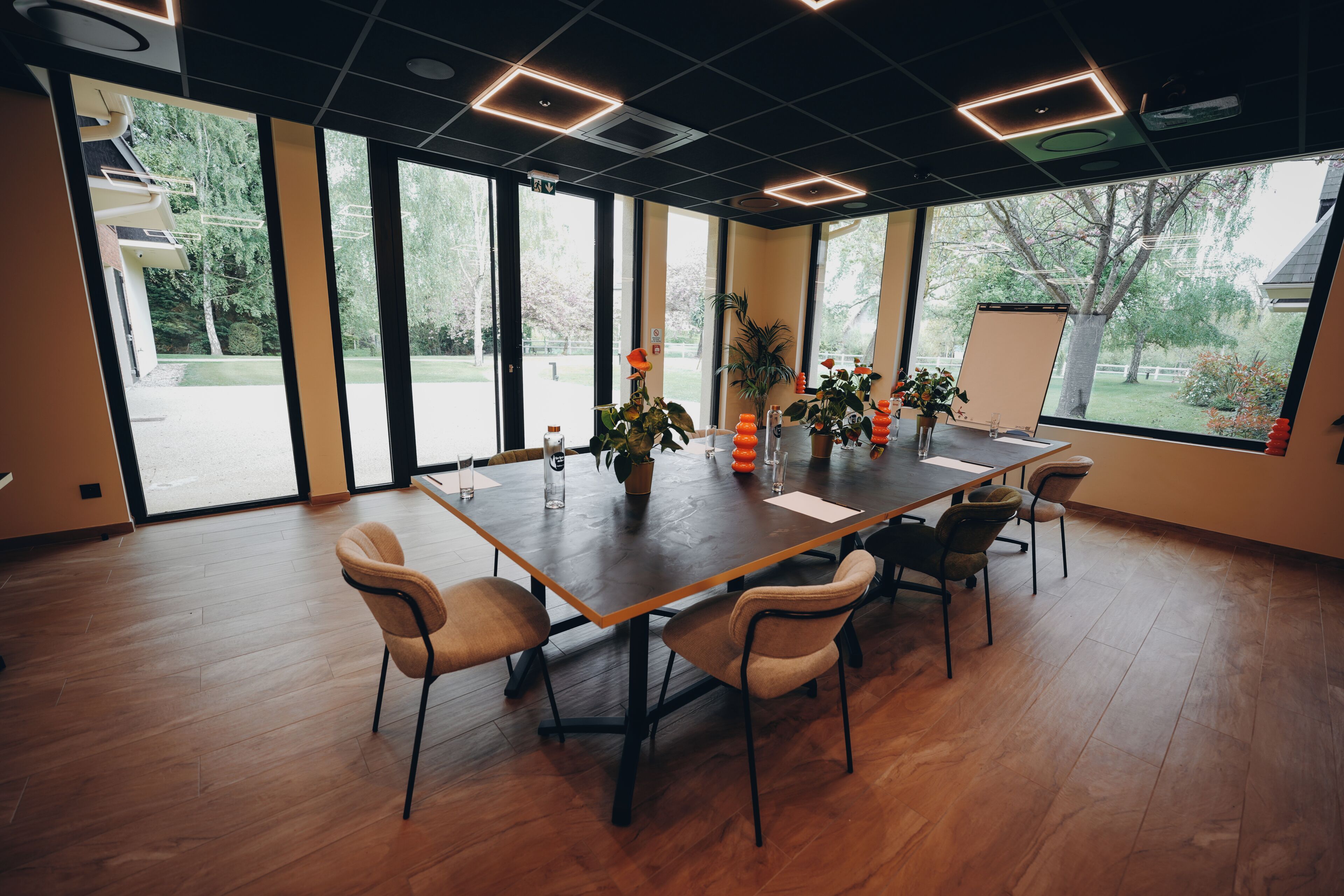 Un salón de conferencias con una gran mesa, sillas, plantas en macetas y vistas amplias a través de grandes ventanales.