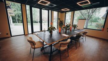 Un salón de conferencias con una gran mesa, sillas, plantas en macetas y vistas amplias a través de grandes ventanales.