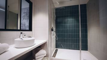 A modern bathroom with a glass-enclosed shower, a white sink, and a mirror with a decorative frame.