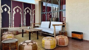 A room with a sofa, ottomans, a table, and a window with curtains.