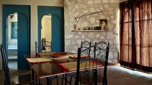 A dining area with a stone wall, a wooden table, and black metal chairs.