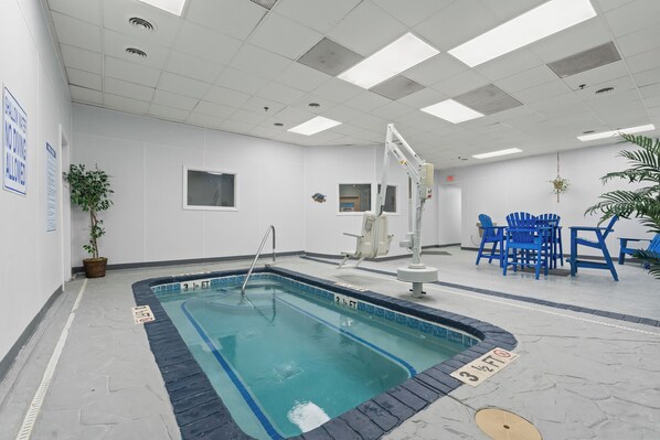 A swimming pool with a lifeguard chair, a blue chair, and a small window.