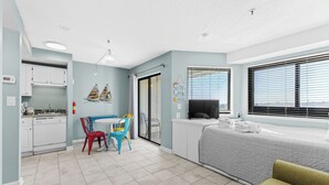 A compact, well-lit room with a kitchenette, a dining area with a table and chairs, a bed with a TV, and large windows with blinds. - T208 at The Myrtle Beach Resort (Myrtle Beach)