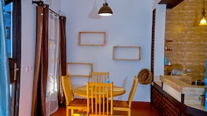 Un comedor con una mesa redonda, cuatro sillas y una lámpara colgante.